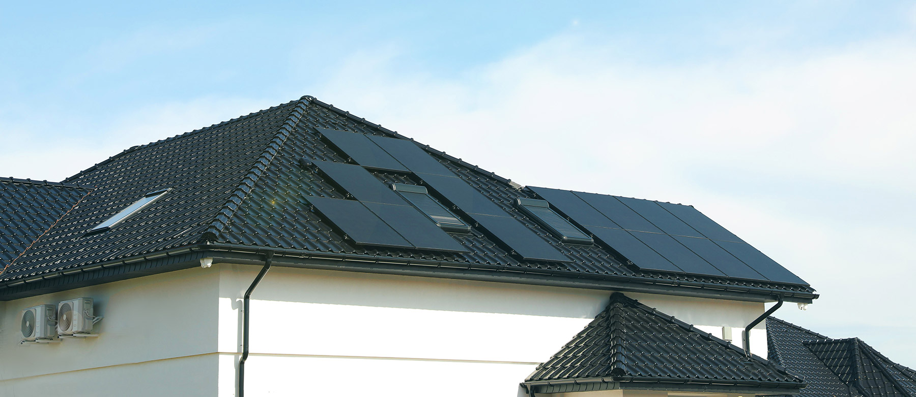 Scanoffice ZNShine Solar ZXM7 -aurinkopaneelit, mustia kaksipuolisia lasi-lasipaneeleja omakotitalon mustatiilisellä katolla.