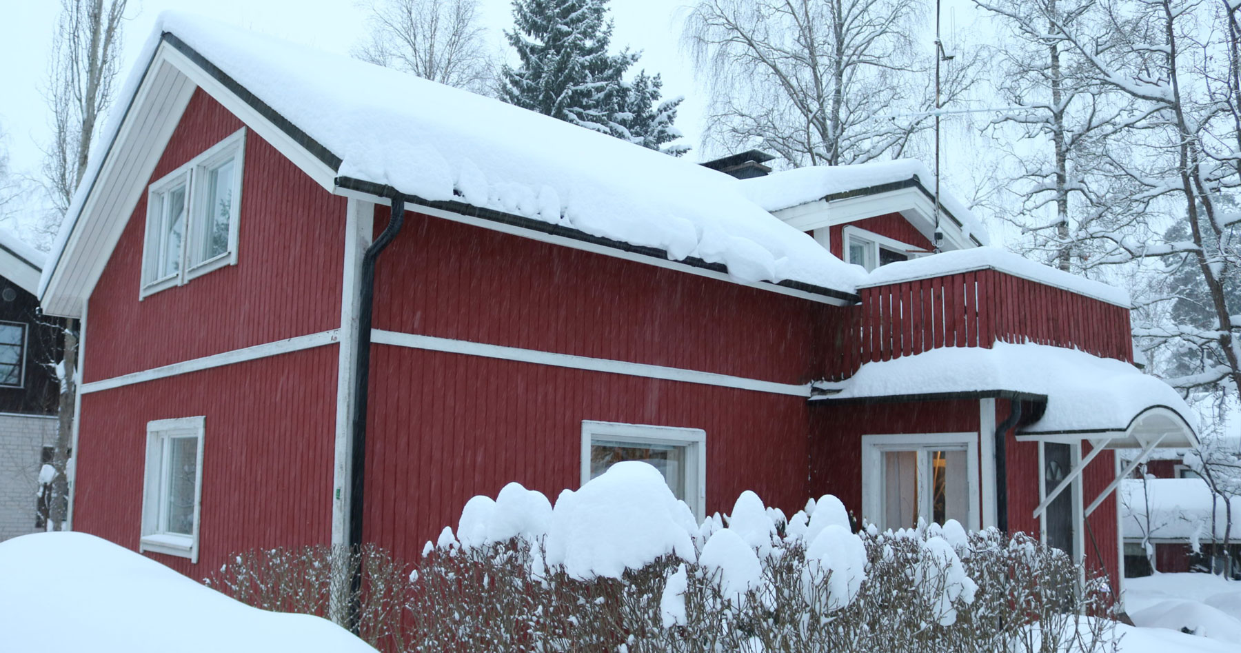 Punainen kaksikerroksinen rintamamiestalo lumiseen vuodenaikaan kuvattuna edestä päin