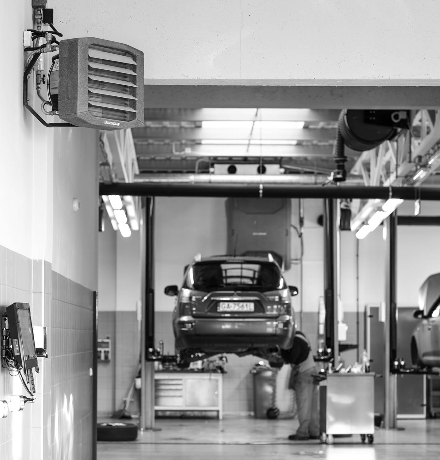 Flowair LEO -kiertoilmakoje autokorjaamossa hyllyjen vieressä, mustavalkoinen kuva.