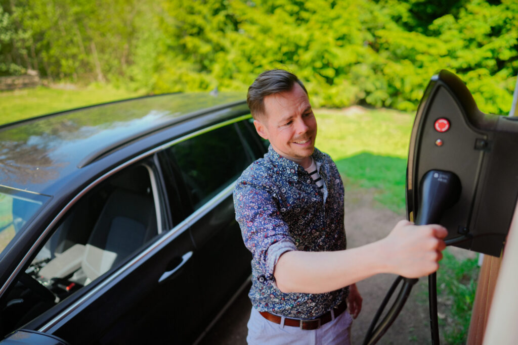 Mies lataa sähköautoa Beny sähköauton latausasemalla
