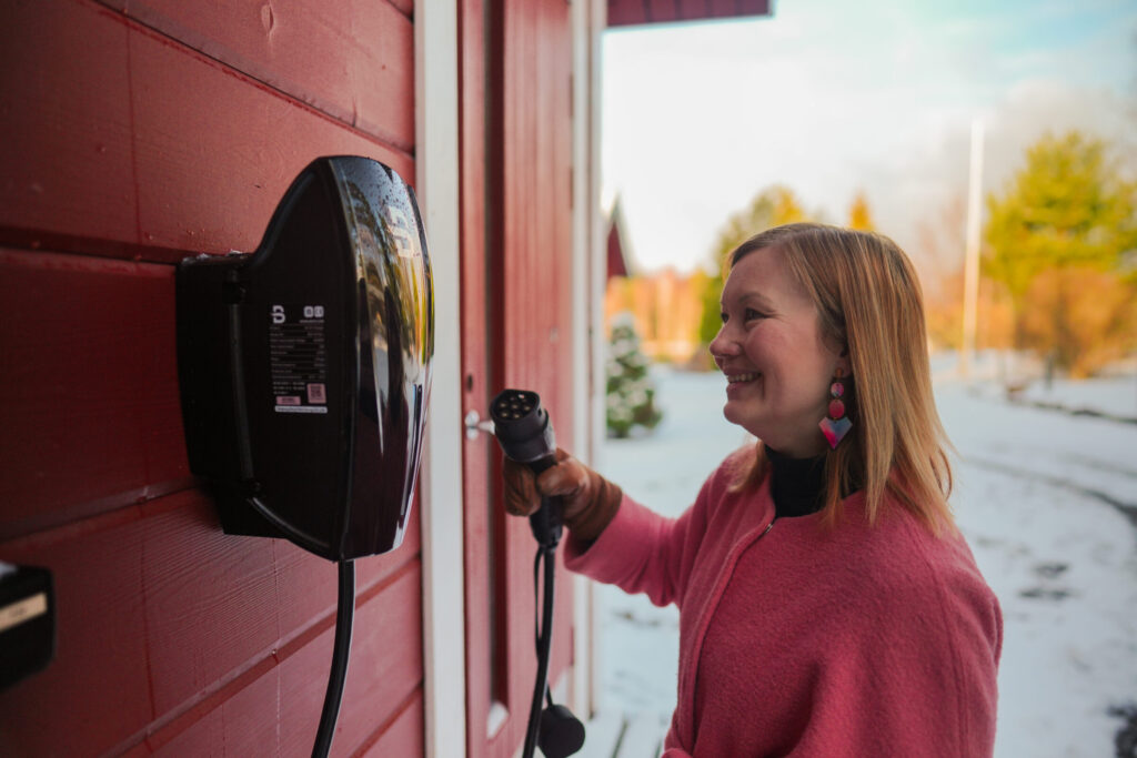 Nainen lataa sähköautoa Beny sähköauton latausasemalla